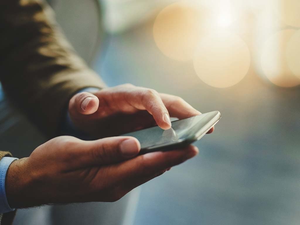 Osoba drži pametni telefon u ruci, gledajući u zaslon s usredotočenim izrazom