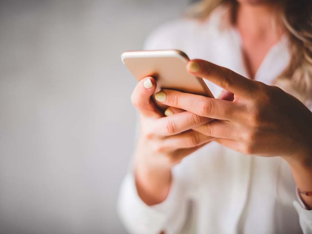 Žena s mobitelom u ruci, uključena u razgovor ili pregledavanje sadržaja na uređaju