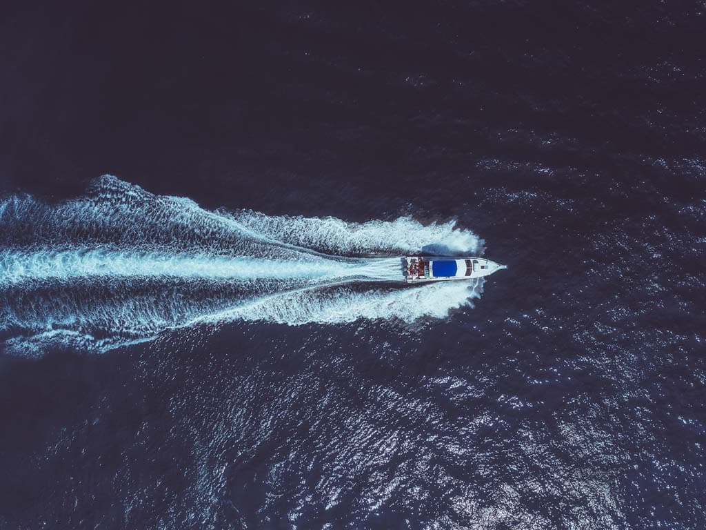 Pogled iz zraka na gliser koji plovi oceanom, stvarajući trag bijele pjene za sobom