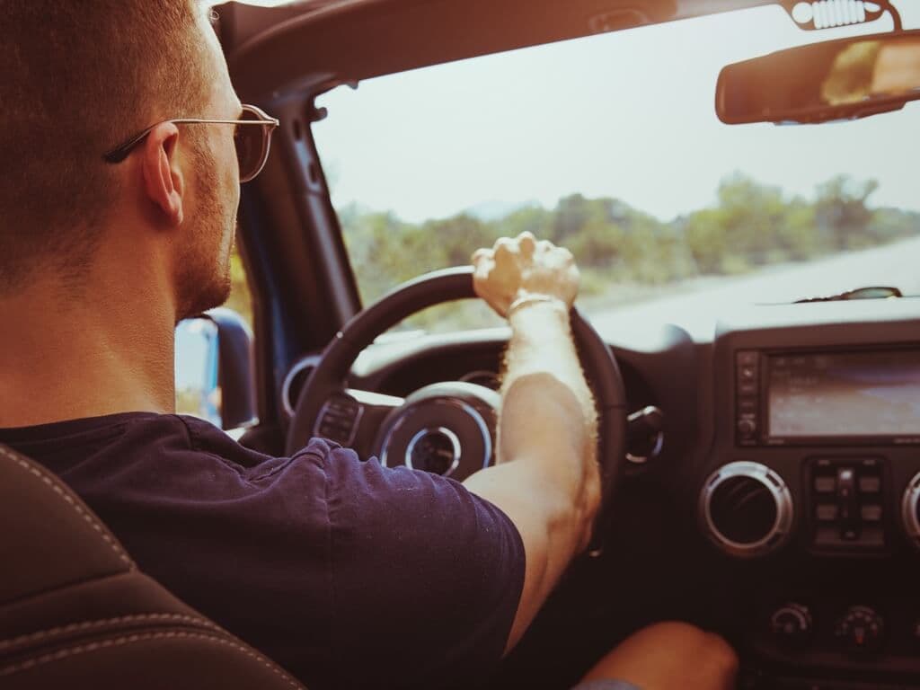 Muškarac za upravljačem automobila, sunčeva svjetlost probija se kroz prozor, osvjetljavajući njegovo lice i unutrašnjost vozila