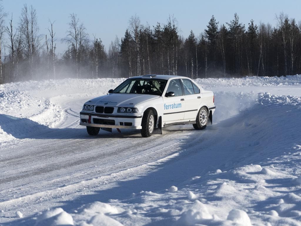 Automobil vozi po snijegom prekrivenoj cesti tijekom zime, okružen mirnim, bijelim krajolikom
