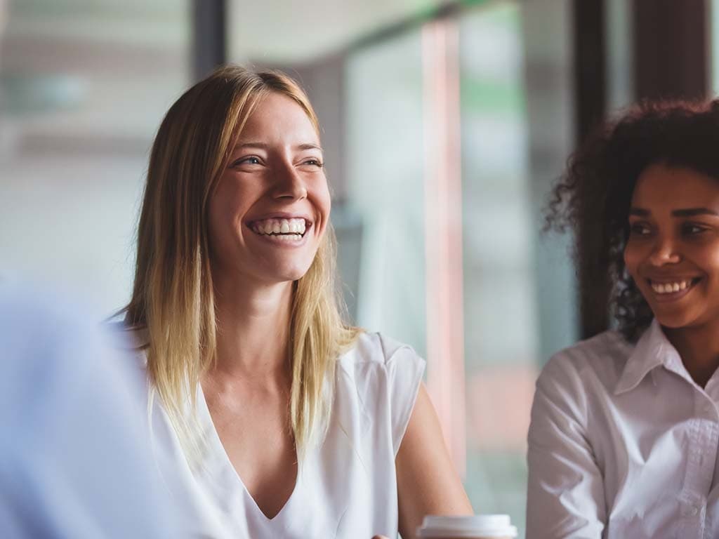 Tri žene smiju se i razgovaraju tijekom sastanka