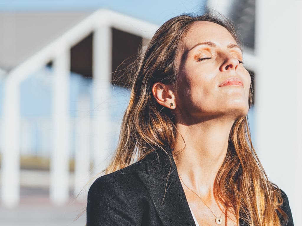 Žena zatvorenih očiju i glave nagnute prema gore, izražavajući osjećaj mira i promišljanja